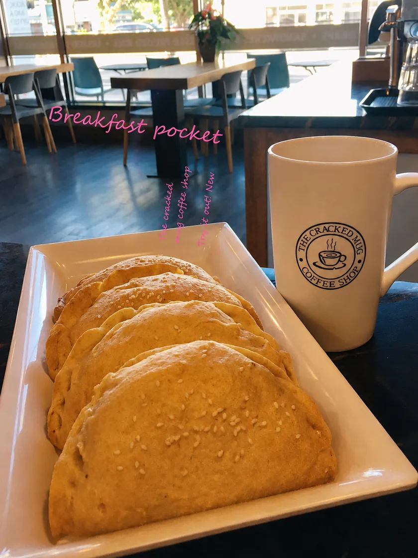 Breakfast pockets on a plate beside a Cracked Mug cup